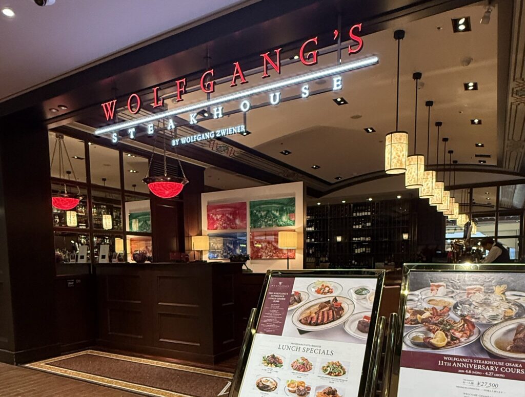 ルクア イーレ10階にあるウルフギャング・ステーキハウス大阪店の店頭。赤いネオンサインとメニューの掲示