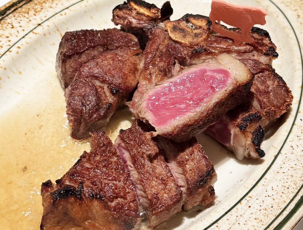 鉄皿に盛られたTボーンステーキ。骨に沿って切り分けられ、断面はピンク色
