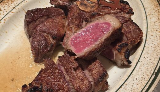 断面がピンク色のTボーンステーキ。骨付きで切り分けられ、牛のピックがのっている