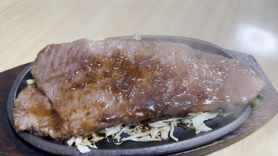 鉄板の上でタレをまとった米沢牛サーロインステーキ