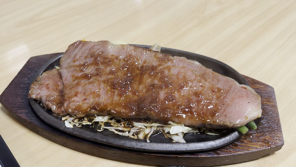鉄板の上でタレをまとった米沢牛サーロインステーキ