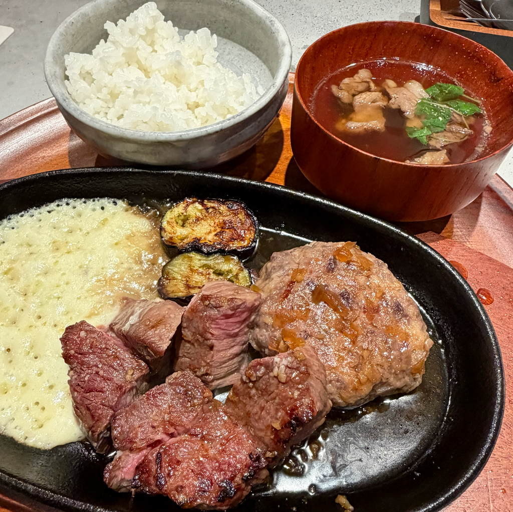 鉄板に盛られた炭火焼きステーキと和牛ハンバーグ、ポテトと焼き野菜。奥にごはんと肉吸い