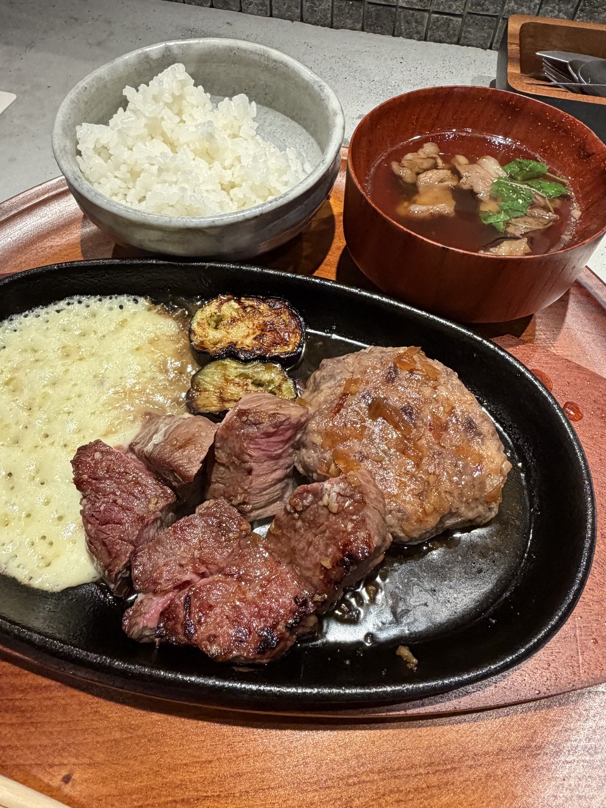 鉄板に盛られた炭火焼きステーキと和牛ハンバーグ、ポテトと焼き野菜。奥にご飯と肉吸い
